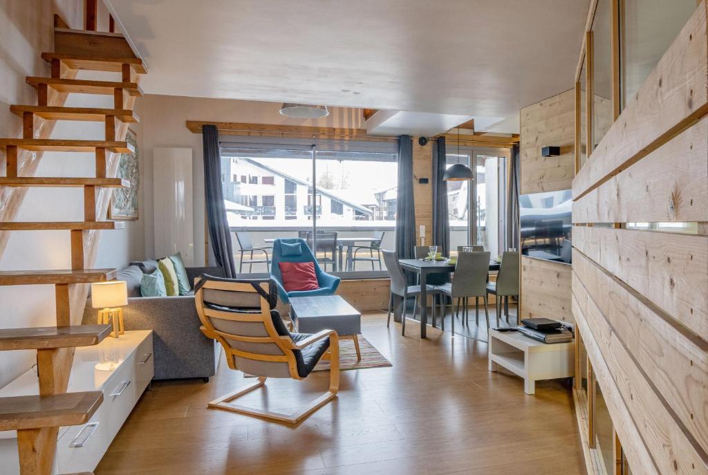 a living room with a staircase and a dining room at Apartment Genevrier - Spacious Balcony with Mont Blanc Views in Chamonix-Mont-Blanc