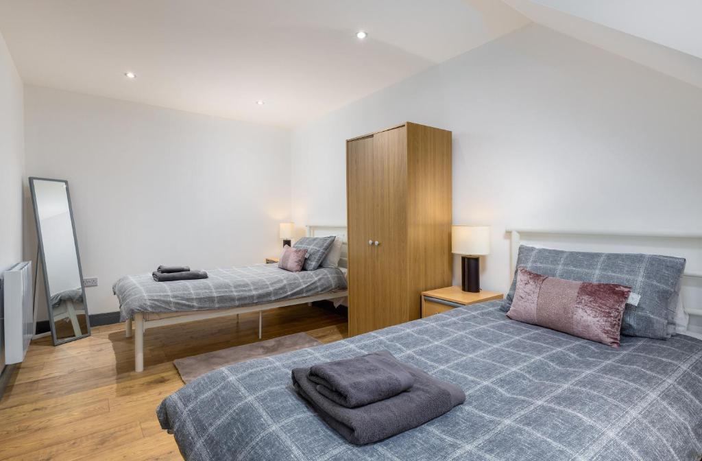 a bedroom with two beds and a cabinet at Cornerstone Cottage in Laurencekirk