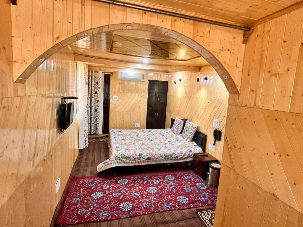 Habitación pequeña con cama y alfombra roja. en Gulmarg View Cottage, en Gulmarg