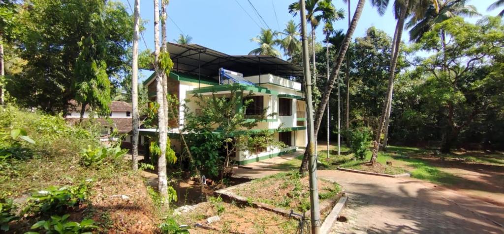 una casa al lado de una carretera con árboles en Coconut Creek Homestay,Kinnigoli, en Mūlki