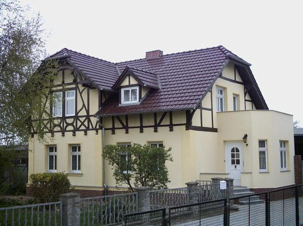 a house with a black roof and a fence at Pension im Oderbruch in Manschnow