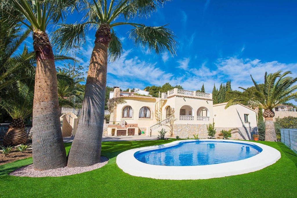 a house with two palm trees and a swimming pool at Villa Sabine - PlusHolidays in Calpe