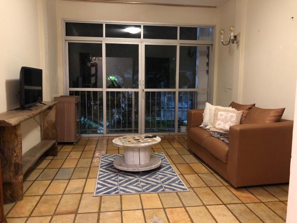 ein Wohnzimmer mit einem Sofa und einem Tisch in der Unterkunft Quarto privado em apartamento. in Vitória