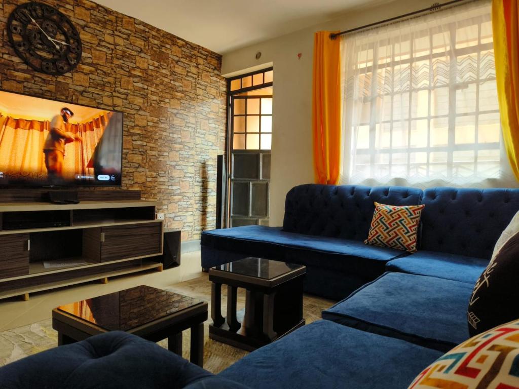 ein Wohnzimmer mit einem blauen Sofa und einem TV in der Unterkunft Trm homes in Nairobi