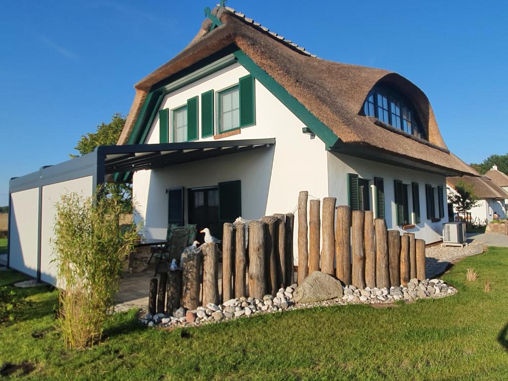 een huis met een rieten dak en een hek bij Ferienhaus Veronika an der Üselitzer Wiek in Mellnitz