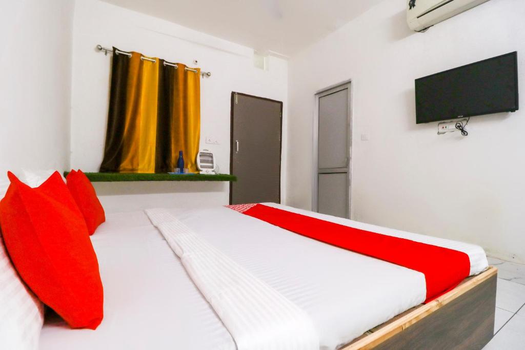 a bedroom with a bed with red pillows and a tv at OYO Hotel Sky Garden in Ludhiana