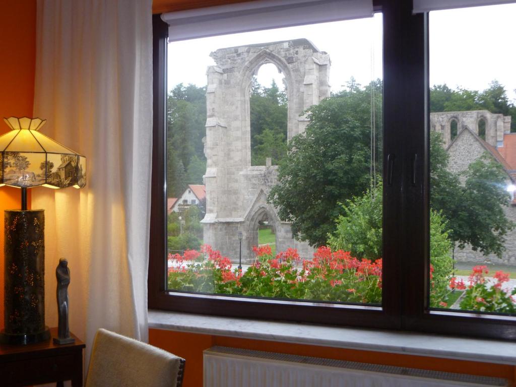 ein Fenster mit Blick auf ein Denkmal und Blumen in der Unterkunft Klosterblick---Refugium---für Erwachsene in Walkenried