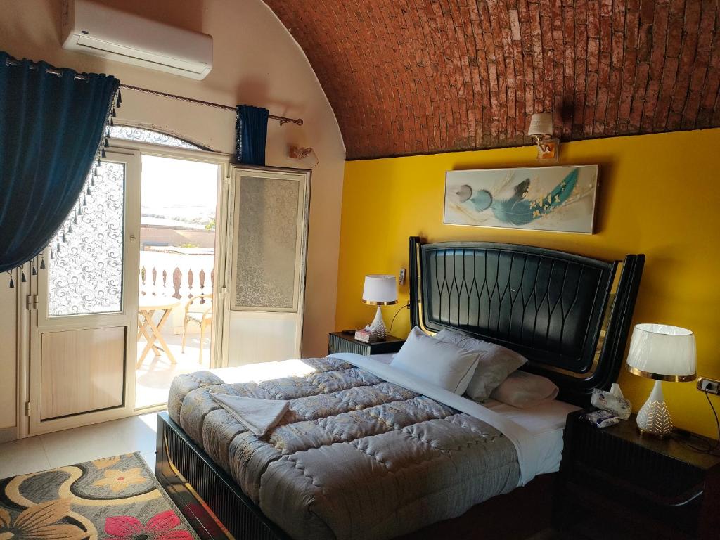 a bedroom with a large bed with a yellow wall at Abu simbel Nubian Guest House in Abu Simbel