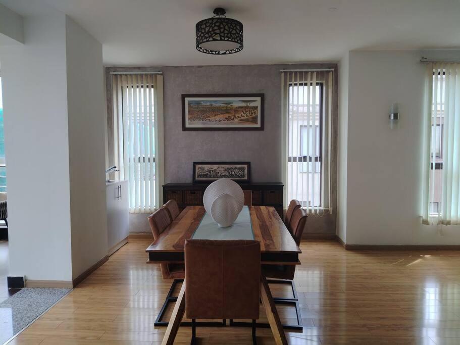 een woonkamer met een houten tafel en stoelen bij Soho 顶层豪华复式 in Nairobi