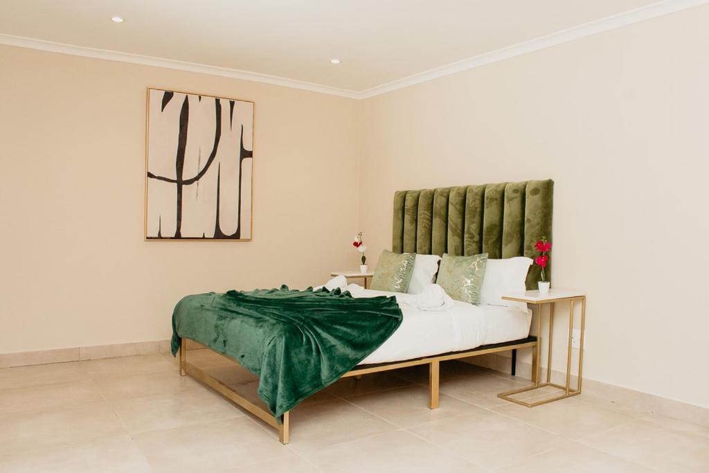 a bedroom with a bed with a green blanket on it at The City Club On Plein in Cape Town