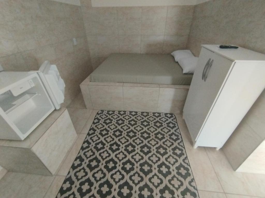 a small room with a bed and a refrigerator at Pausada do Gilmar in Ribeirão
