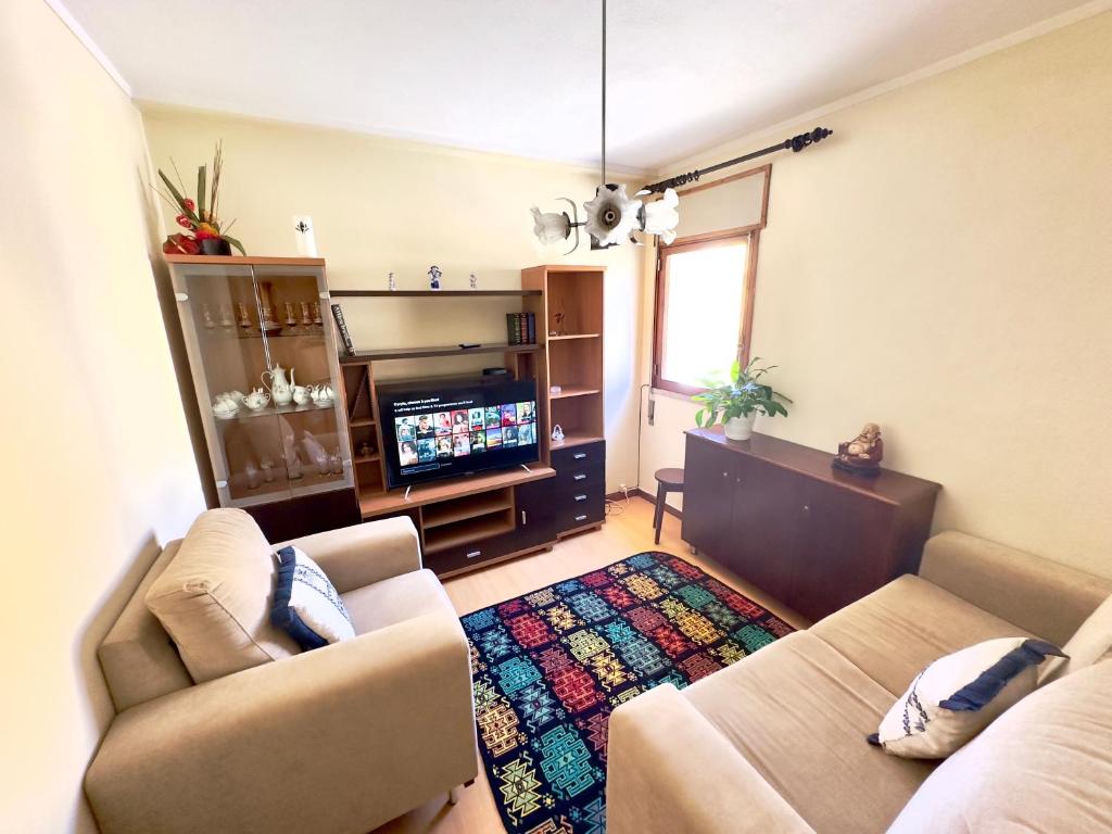 uma sala de estar com um sofá e uma televisão em Cozy T2+1 2 minutes from the beach em Buarcos