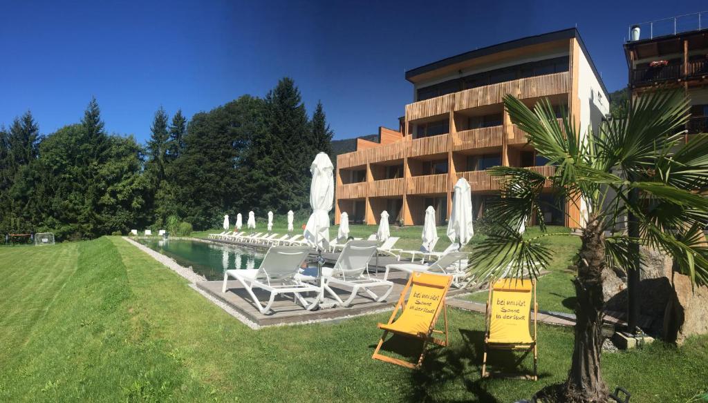 a building with a pool with chairs and a fountain at Wildauers Haidenhof STAY & SLEEP in Lienz