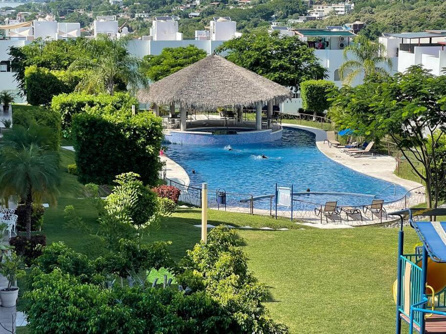 una gran piscina con sombrilla de paja en Casa vacacional Tequesquitengo, en Tequesquitengo