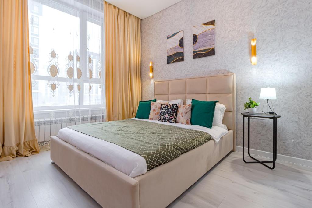 een slaapkamer met een groot bed en een raam bij Комфортабельная квартира в ЖК Apple City in Astana