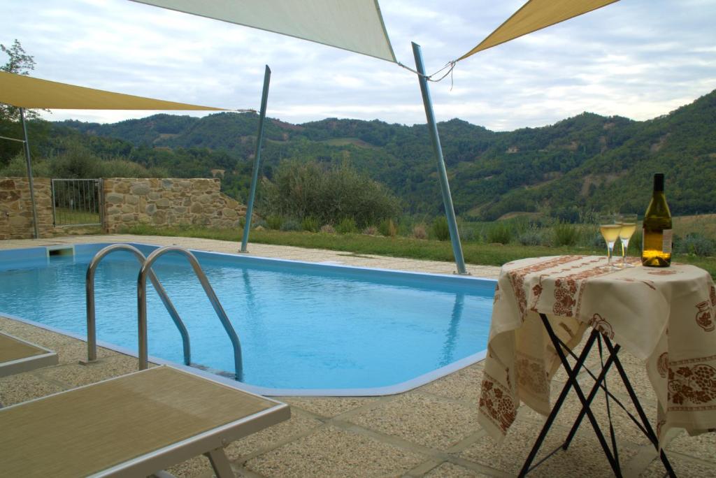 a table with wine glasses and an umbrella next to a swimming pool at Villa Podere Quartarola in Modigliana