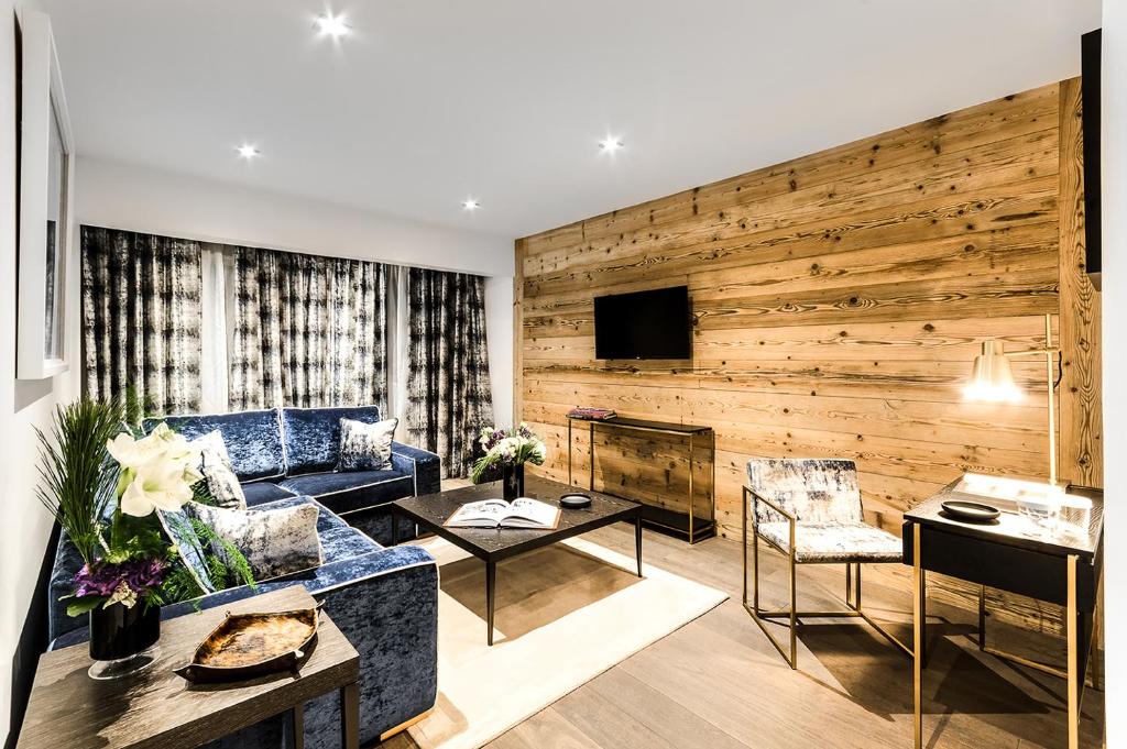 a living room with a blue couch and a wooden wall at Hôtel La Sivolière in Courchevel