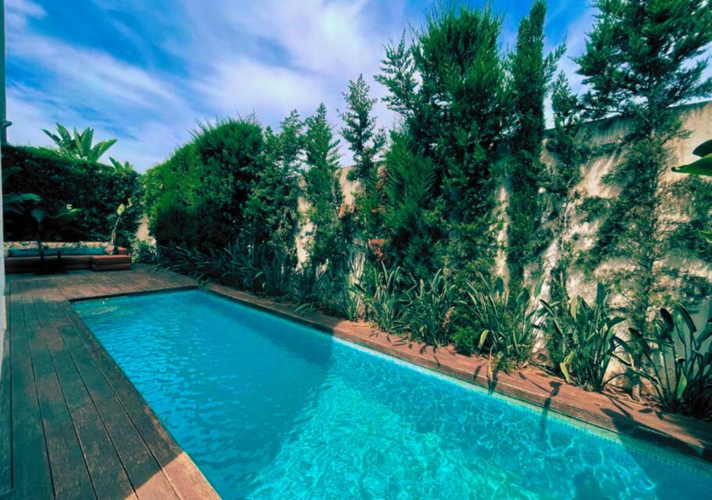 a swimming pool in front of a wall with trees at Cozy Villa With Pool and Indoor Fireplace in Casablanca
