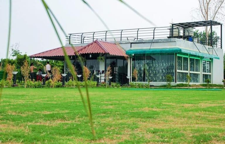 a house with a green field in front of it at The River Side Resort & Farm in Noida
