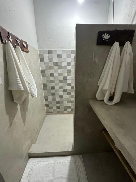 uma casa de banho com toalhas brancas penduradas numa parede em Chalé da Mata Trancoso em Trancoso