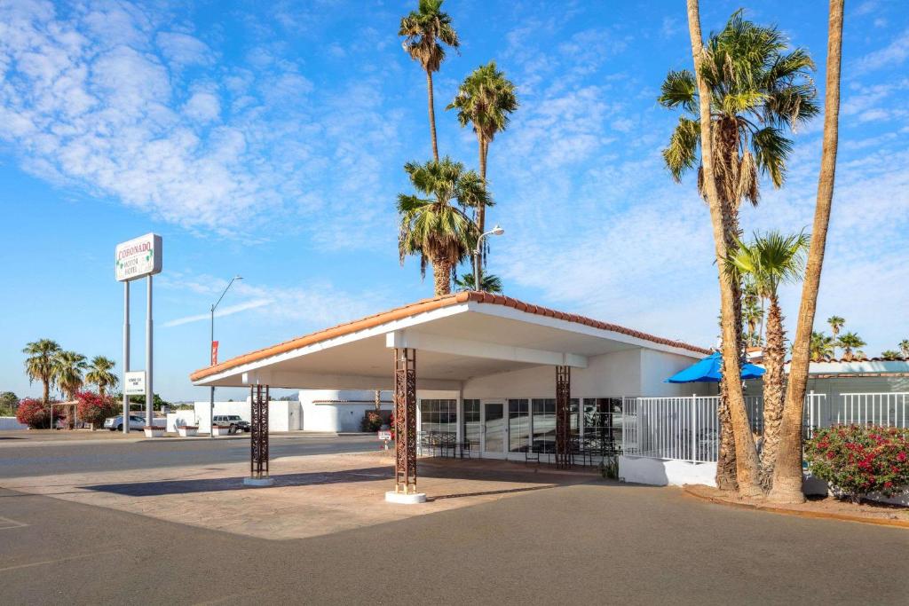 um posto de gasolina com palmeiras num parque de estacionamento em Coronado Motor Hotel, a Travelodge by Wyndham em Yuma