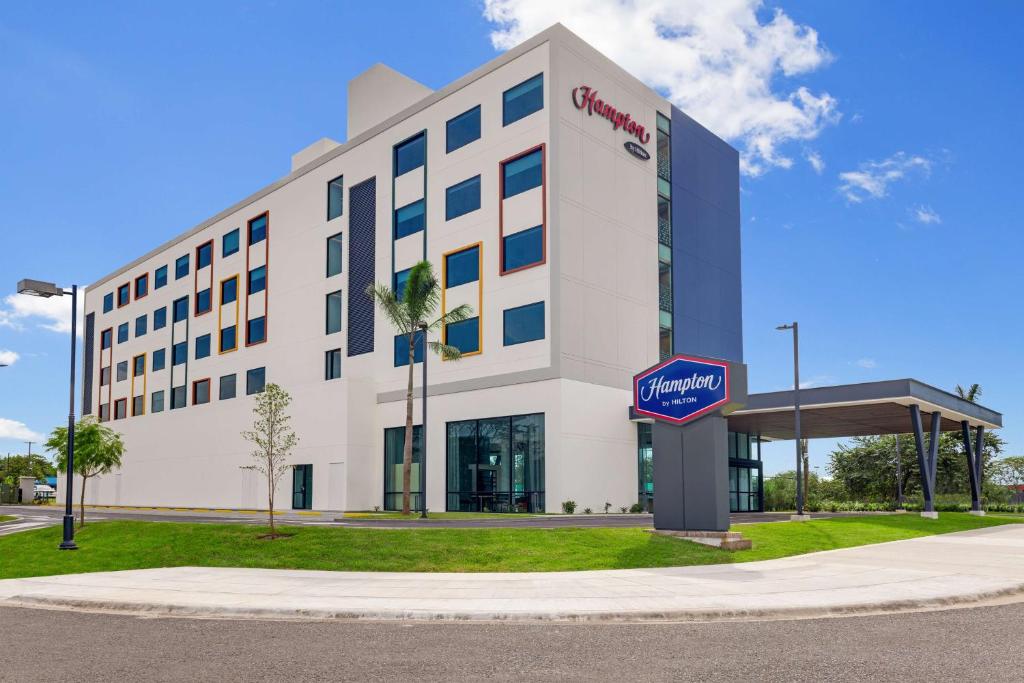 un gran edificio blanco con un cartel delante en Hampton By Hilton Guanacaste Airport en Liberia