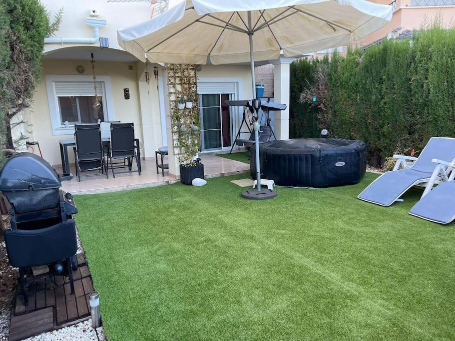 a backyard with an umbrella and a grill and a lawn at Apto. residencial en Murcia in Murcia