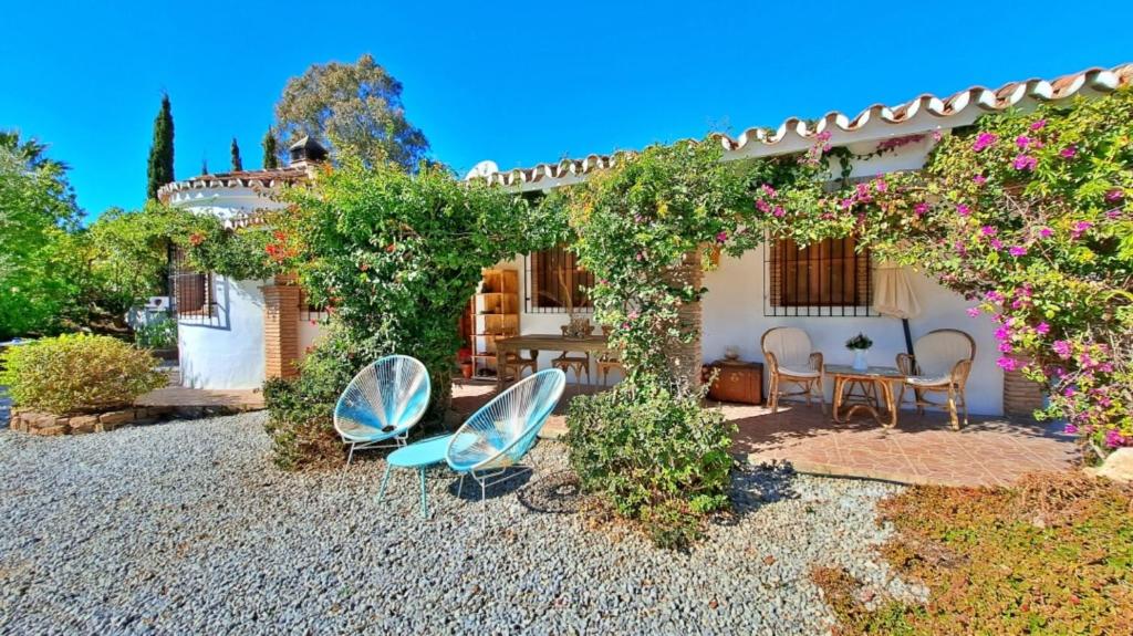 un patio con 2 sillas y un arco con flores en La Perla Andaluza, en Alcaucín