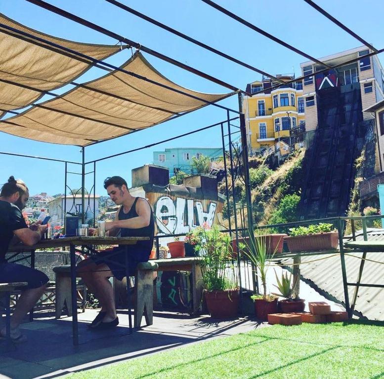 two men sitting at a table under an umbrella at Casa Elias Hostel-Av Elias in Valparaíso