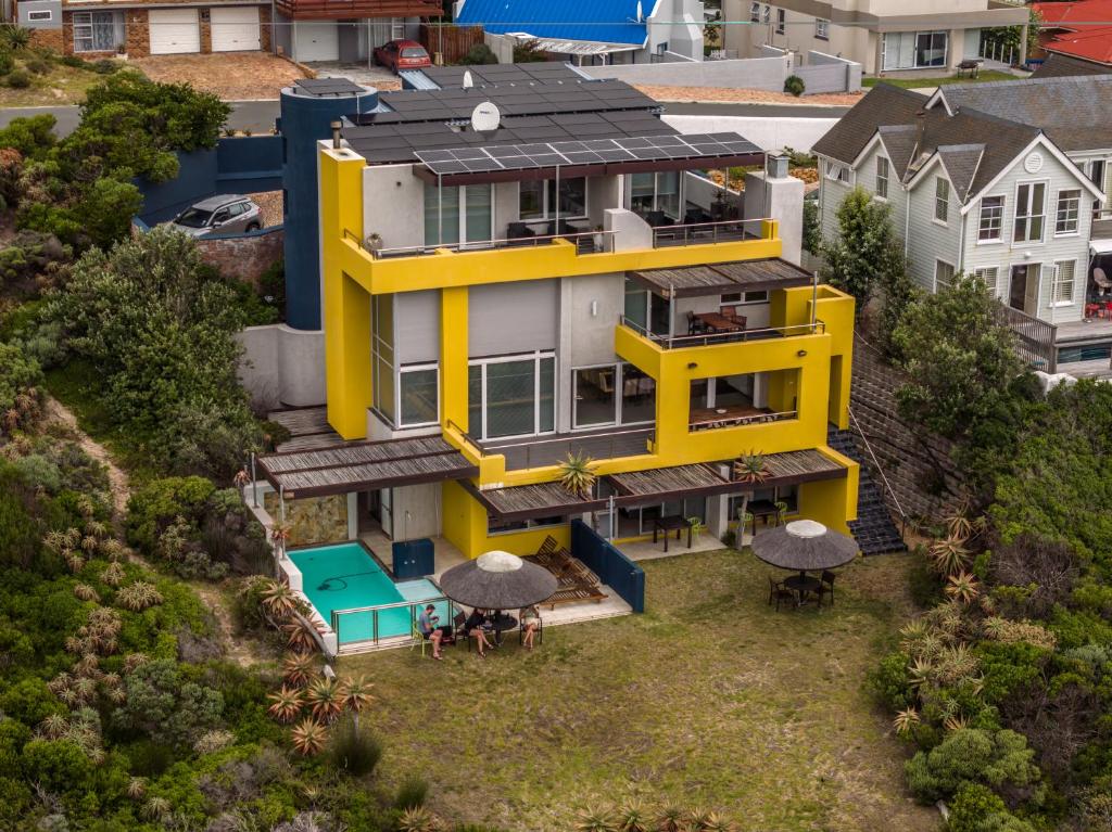 an aerial view of a yellow house with tables and umbrellas at Crayfish Lodge Sea & Country Guest House in Gansbaai