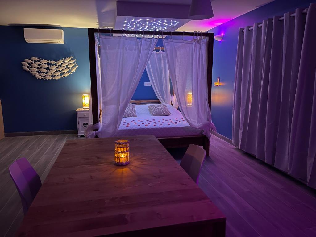 a room with a bed with a table and purple lighting at La Paillote Exotique Spa in Beaucaire