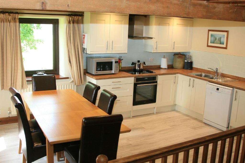 a kitchen with a wooden table and a table and chairs at Saddleback Barn in Penrith