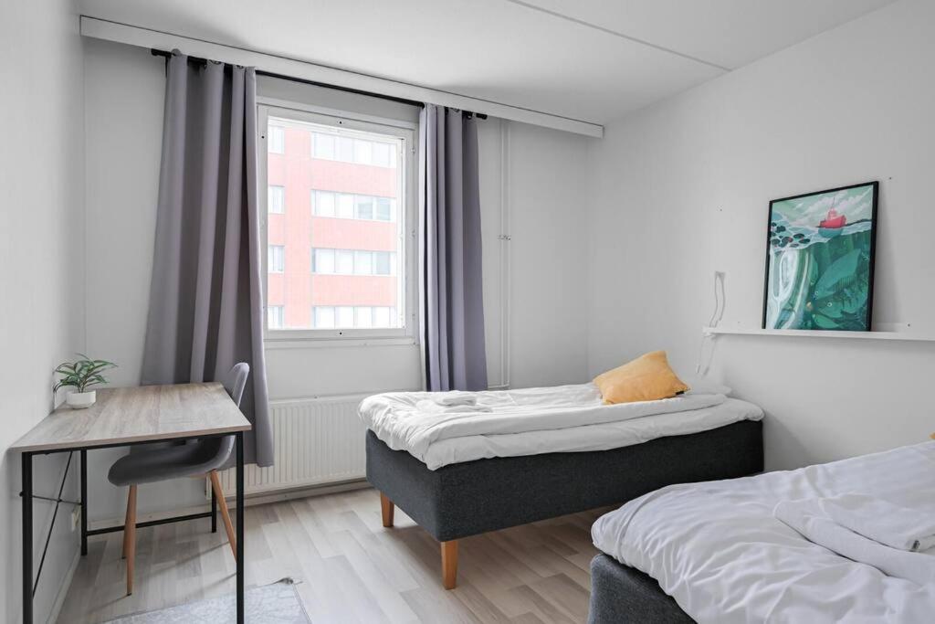 1 Schlafzimmer mit 2 Betten, einem Schreibtisch und einem Fenster in der Unterkunft Kotimaailma- Valoisa kaksio jopa viidelle in Helsinki