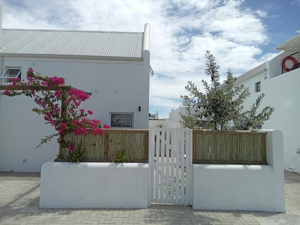 a white house with flowers on a fence at Spacious loft in Paternoster