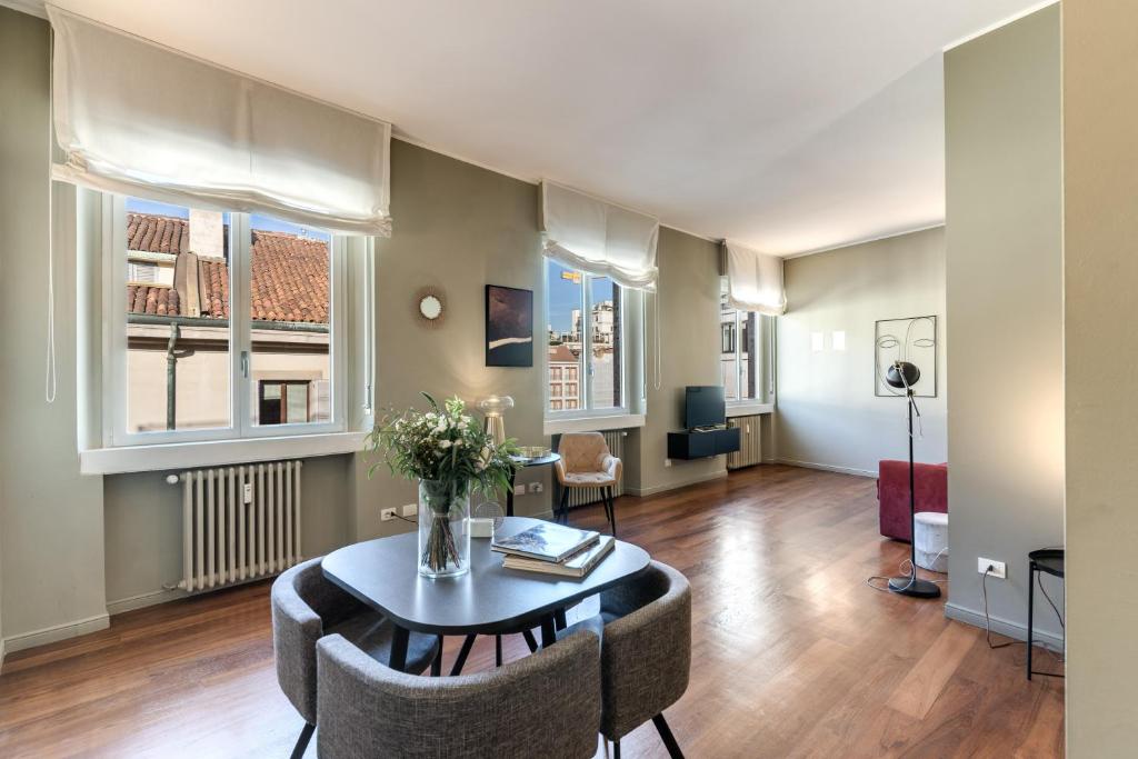 ein Wohnzimmer mit einem Tisch, Stühlen und Fenstern in der Unterkunft Suite Santa Tecla in Mailand