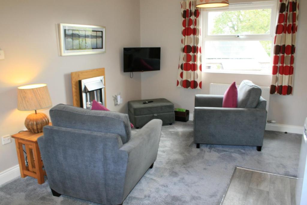彭里斯的住宿－Sharp Edge，客厅配有两把椅子和电视