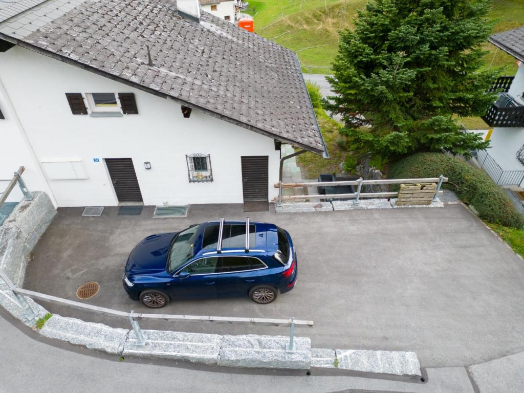 ein blaues Auto parkt auf einem Parkplatz neben einem Haus in der Unterkunft Casa Anita in Laax-Murschetg