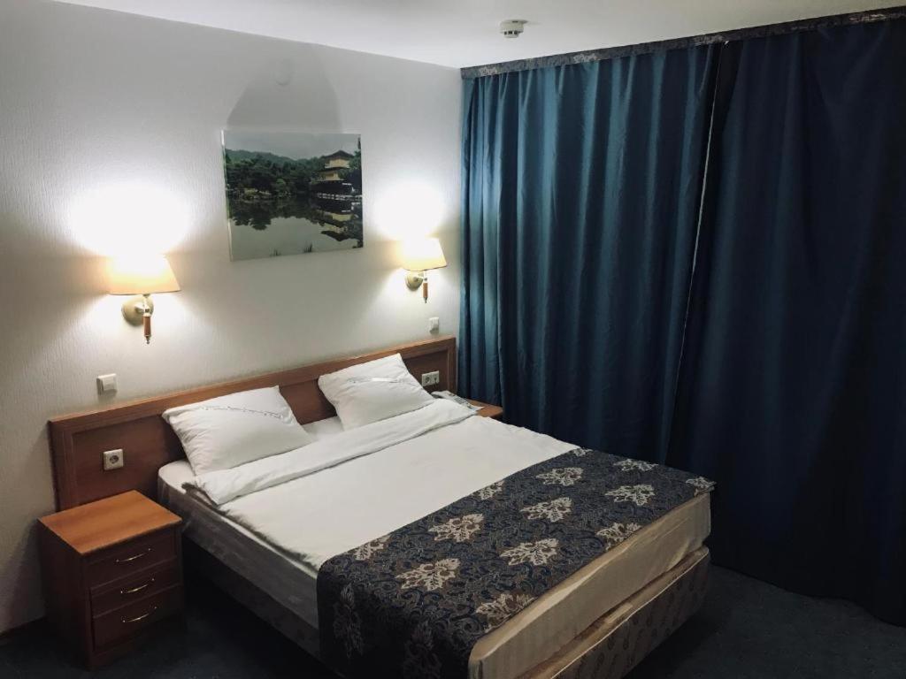 um quarto com uma cama com uma cortina azul e uma cama sidx sidx sidx em Green Hotel em Atyrau