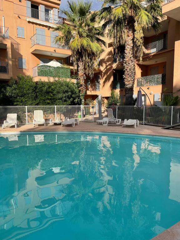 uma piscina em frente a um edifício com palmeiras em GRIMAUD Vue piscine em Grimaud