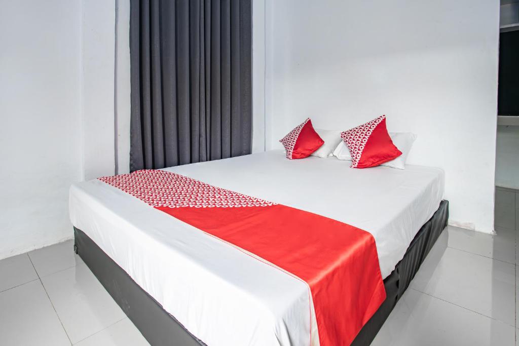 Un dormitorio con una cama con almohadas rojas. en OYO 93476 Owo Guest House Syariah, en Jambi