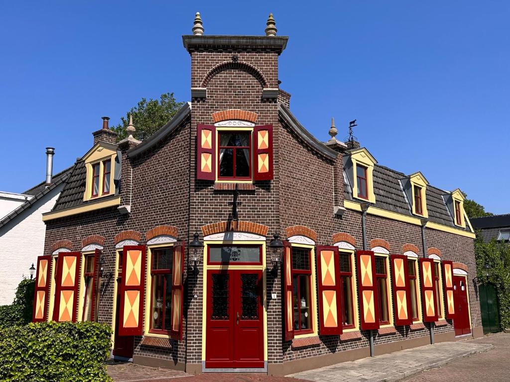 un grande edificio in mattoni con porte e finestre rosse di BnB 't Ambacht - Boutique Hotel a Hendrik-Ido-Ambacht