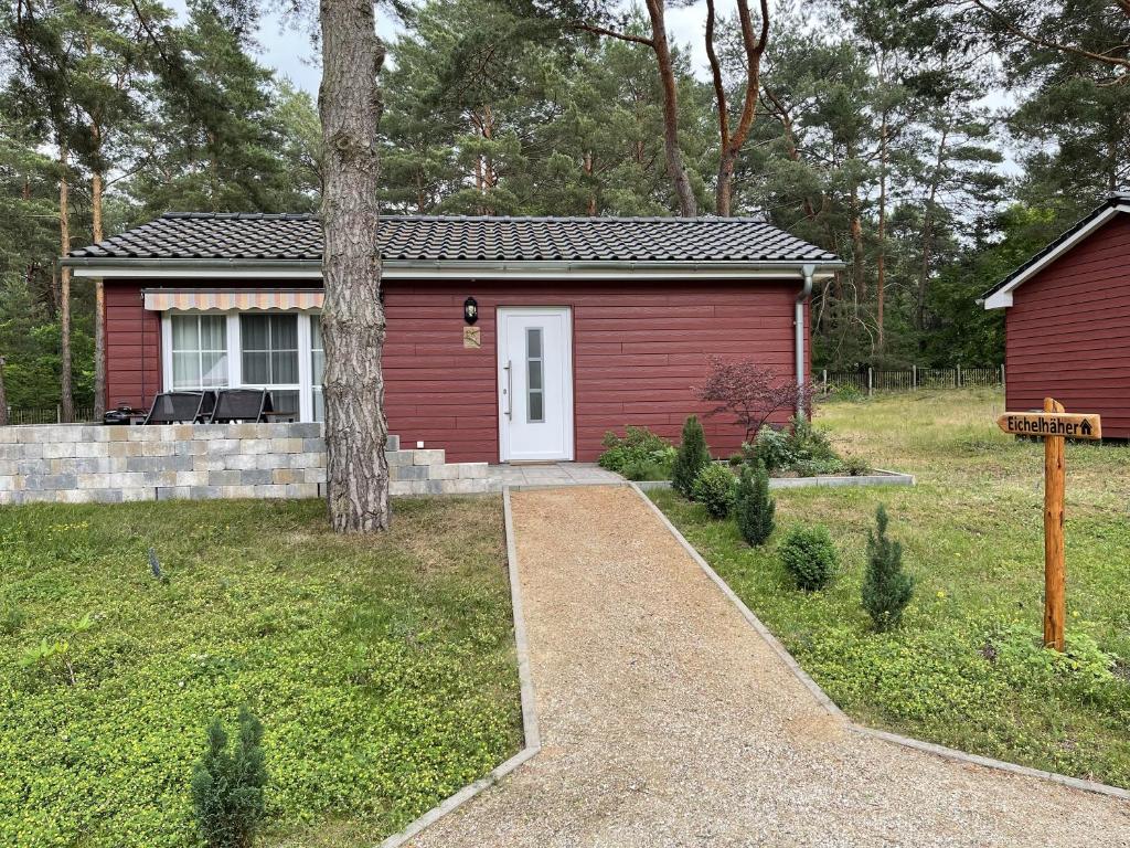 una pequeña casa roja con una puerta blanca en Ferienhaus Eichelhäher, en Zossen