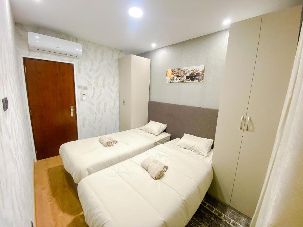 duas camas num pequeno quarto com lençóis brancos em ODIVELAS METRO RESIDENCE em Odivelas