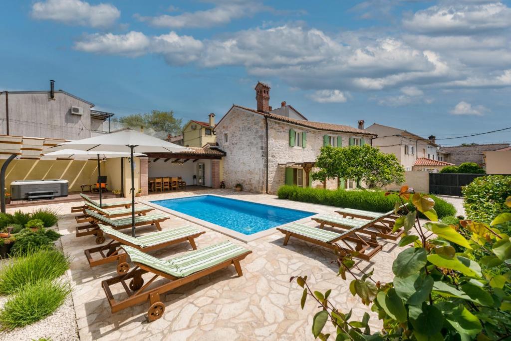 a swimming pool with lounge chairs and an umbrella at Villa Katja near Pula with whirlpool only 3 km from the beach in Krnica