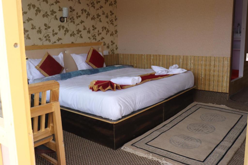 a bedroom with a bed with white sheets and red pillows at The hidden heaven cottage pangong merak in Meruk