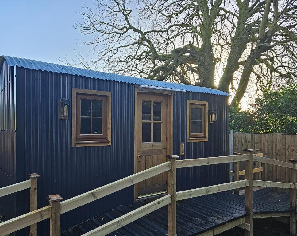 een blauw tiny house met een houten terras bij Rectory Roost in Spalding