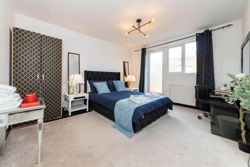 een slaapkamer met een blauw bed en een raam bij Well Equipped Apartment for Relocators and Contractors in Reading
