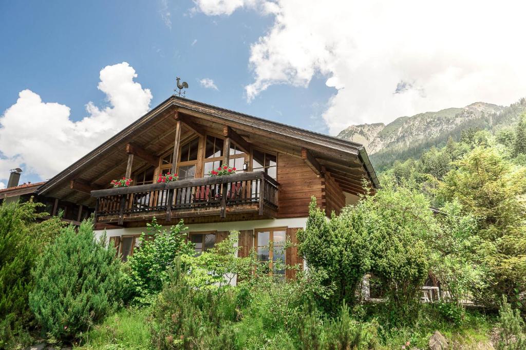 a log house with a balcony with flowers on it at Alpenhaus Oberstdorf in Oberstdorf