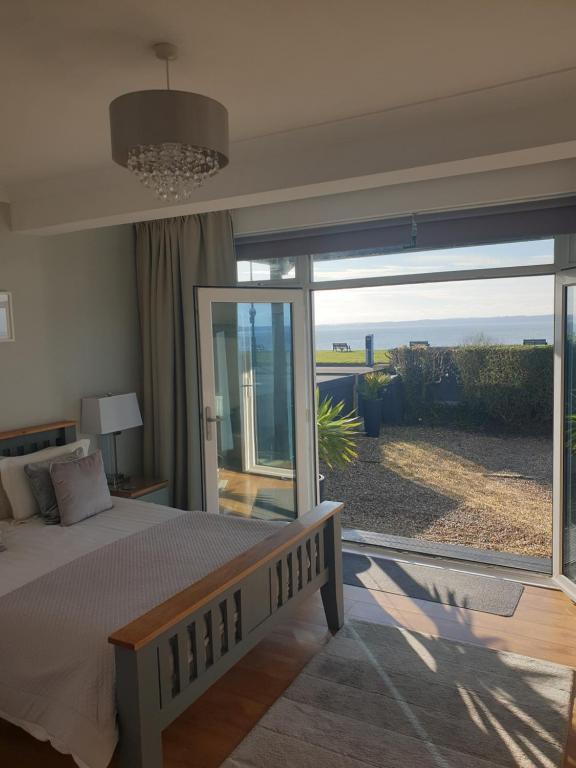 Schlafzimmer mit einem Bett und einem großen Glasfenster in der Unterkunft The Waters Edge in Lee-on-the-Solent