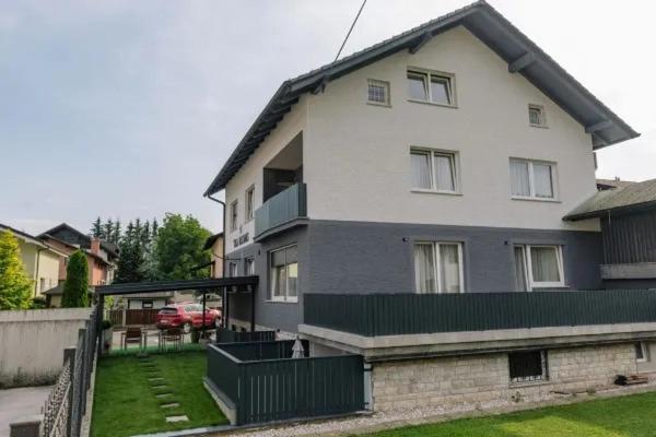 a large white house with a fence in a yard at EnDi Rooms in Ljubljana